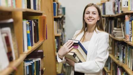 Studentessa tra gli scaffali di una biblioteca
